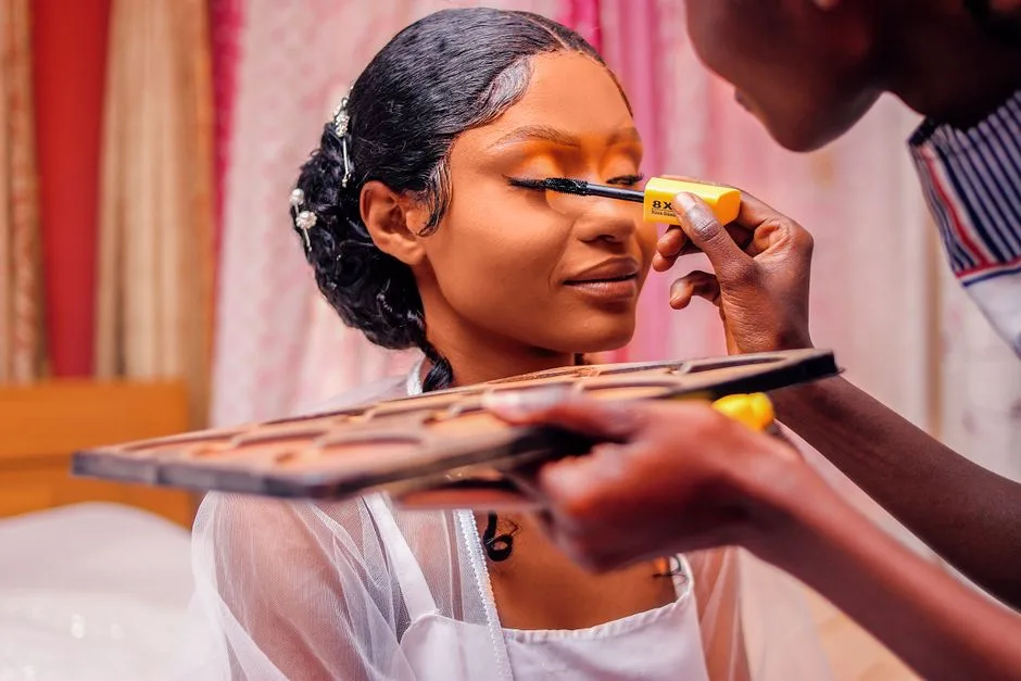 A makeup artist carefully applies mascara to a bride's eyes, showcasing beauty and skill.